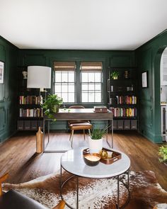 a living room with green walls and wooden flooring, a coffee table in the center