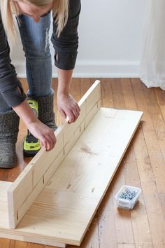 a woman sanding down some wood on the floor next to a drill and screwdriver