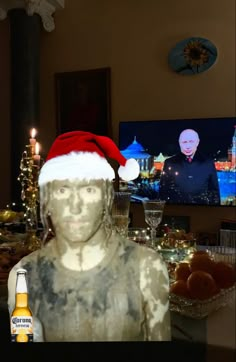 a man wearing a santa hat in front of a television with an image on it