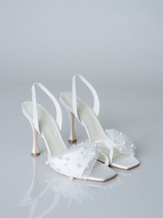 a pair of white high heel shoes with pearls on the toe and heels are shown