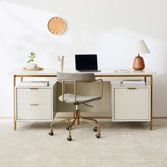 a desk with a laptop on it next to a lamp and a clock above it