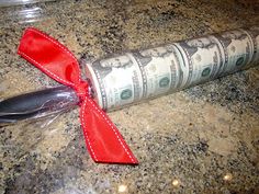 a roll of money wrapped in red ribbon sitting on top of a granite countertop