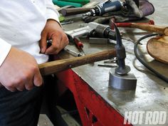 a man holding a hammer in his right hand while standing over a workbench