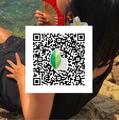 a woman sitting on the ground holding a red fan and a qr code sticker