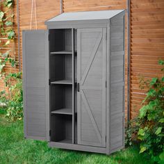 an outdoor storage cabinet in the grass next to a fence