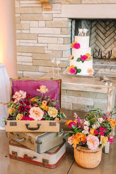 two suitcases with flowers in them sitting next to each other on a table near a fireplace