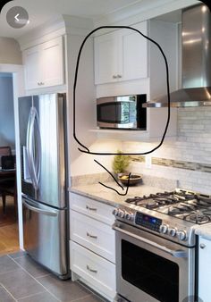 a kitchen with white cabinets and stainless steel appliances, including a silver refrigerator freezer