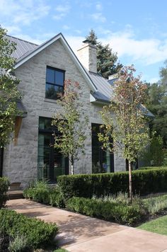 a house with hedges and trees in the front yard