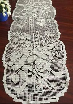 a table runner with white crocheted doily on it and a potted plant in the background