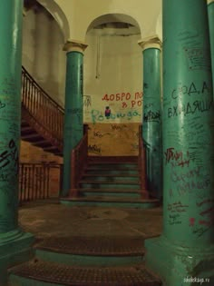 an old building with graffiti all over the walls and floor, along with several green pillars