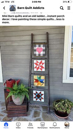 an old ladder is decorated with patchwork quilts and potted plants on the front porch