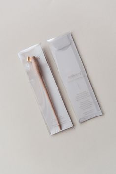 an open box with a toothbrush in it next to a package on a white surface