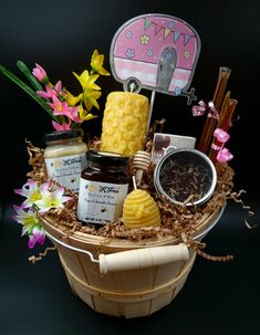 a basket filled with honey, jams and flowers