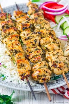 chicken skewers with rice and vegetables on a plate