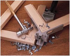 a hammer and some screws on a wooden table next to a piece of wood