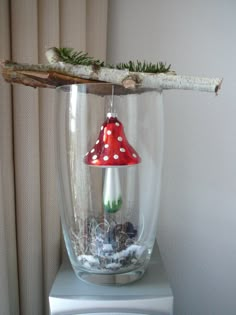 a glass vase with a red and white mushroom in it