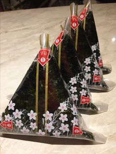 three triangle shaped bags with flowers on them sitting on a counter top next to each other