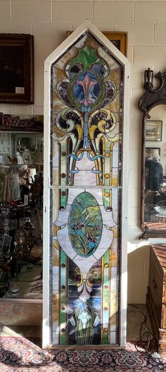 an ornate stained glass window in the corner of a room with other antique items on display