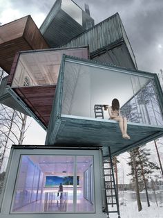 a woman sitting on top of a building made out of windows and stairs in the snow