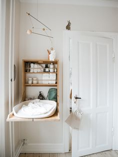 a white bathroom with a wooden shelf and open door