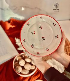 a person holding a plate with cherries on it