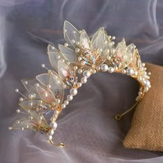 a gold tiara with pearls and butterflies on it's headband, resting on a pillow