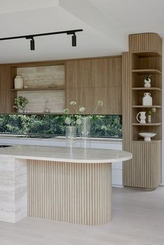 a kitchen with an island counter and shelves in the back ground, surrounded by wood paneling