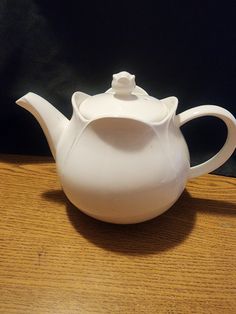 a white tea pot sitting on top of a wooden table