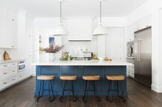 a kitchen with white cabinets and blue island