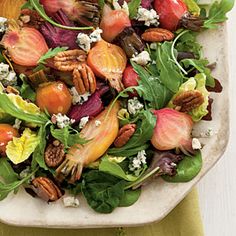 a white plate topped with salad covered in lots of toppings on top of a green cloth