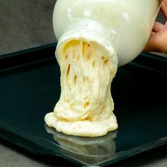 a person pouring milk into a container on top of a black tray