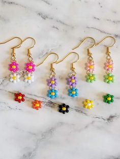 six pairs of flower earrings sitting on top of a marble counter with gold earwires