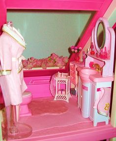 a doll house with pink furniture and accessories in the room, including a sink, toilet, mirror and bathtub