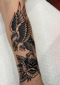 a black and white tattoo on the arm of a man with an eagle, roses and leaves