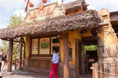 a man standing in front of a building with a thatched roof