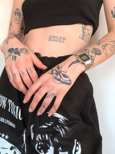 a woman with tattoos on her arms and leg, wearing black sweatpants while holding onto an apple watch