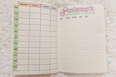 an open planner book sitting on top of a white blanket with the words poshmark written in pink and green