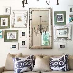 a living room filled with furniture and framed pictures on the wall above a mirror over a couch