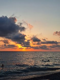 people swimming in the ocean at sunset