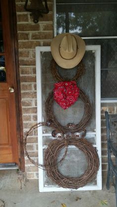 a couple of wreaths with cowboy hats on top of them and rope wrapped around the front door