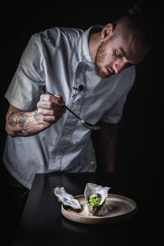 a man is sprinkling some food on top of a plate with a knife and fork