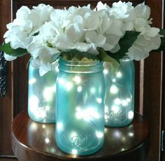 three mason jars filled with white flowers on top of a table