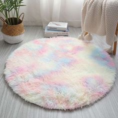 a round rug with pastel colors on the floor in front of a white window