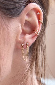 a close up of a person with ear piercings on their ears and wearing gold jewelry