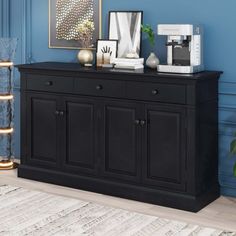 a black sideboard in a blue room with pictures on the wall and other decorations