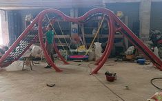 a man standing next to a red and blue playground slide in a garage with other equipment