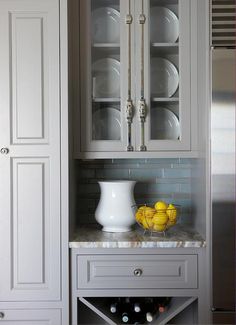 a kitchen with gray cabinets and white dishes