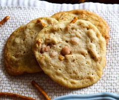 two cookies are on a napkin next to some pretzels