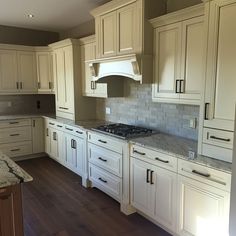 a kitchen with white cabinets and marble counter tops on a hardwood flooring area in front of an oven