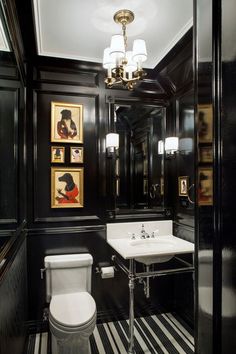 a black and white bathroom with striped flooring, framed pictures on the wall and a pedestal sink